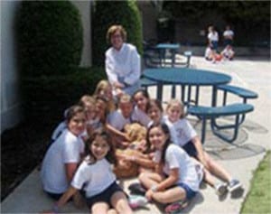 Jodi Dog surrounded by owner/Principal Virginia Devine and Rosarian students