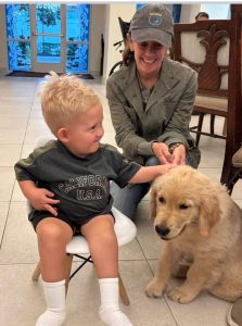 Smiling child and woman with playful puppy indoors