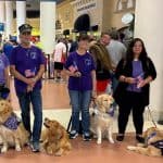 People with service dogs holding American flags in airport.