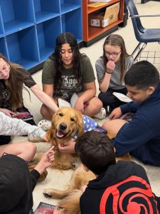Students petting therapy dog in classroom circle